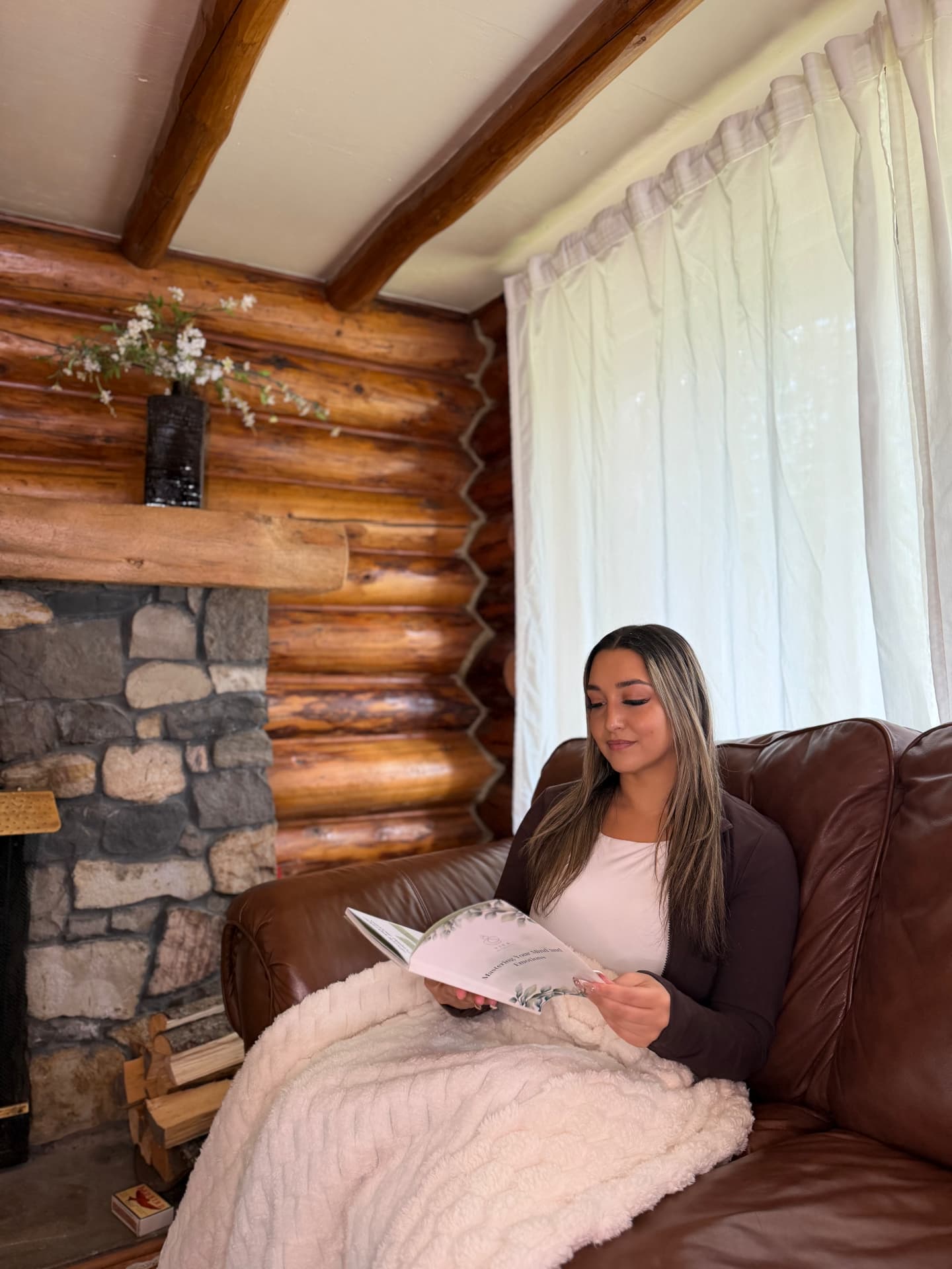 A Vita guest reading beside the stone fireplace in the Bragg Creek cabin